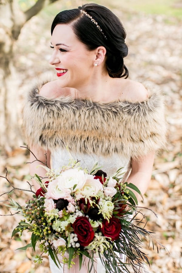 Bride with fur shrug and bouquet smiling