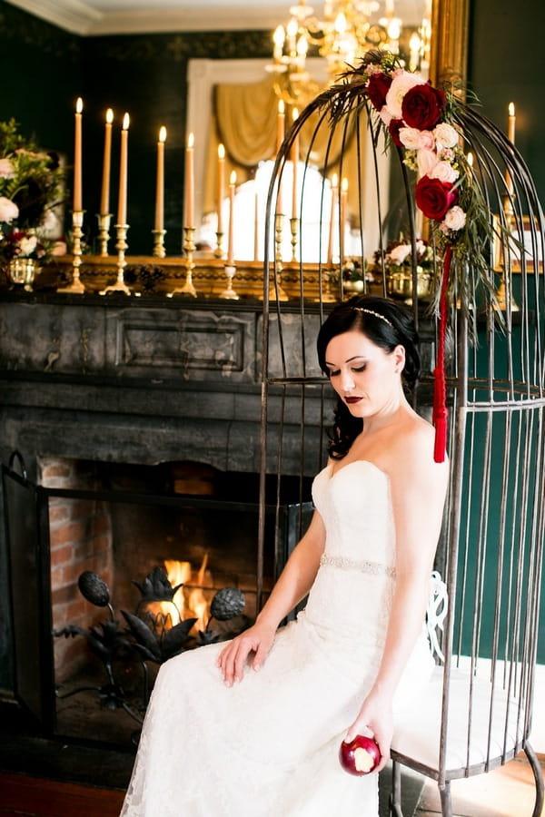 Bride sitting in birdcage swing chair by fire
