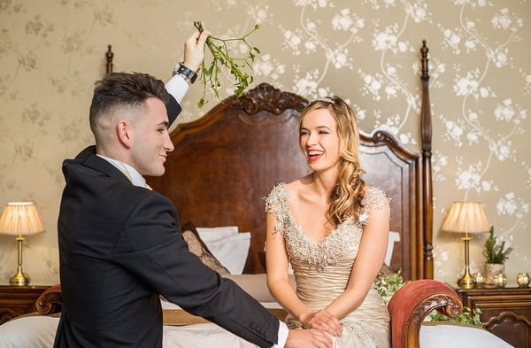 Groom holding mistletoe over bride