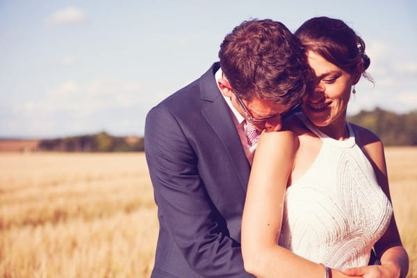 Groom kissing bride on the shoulder