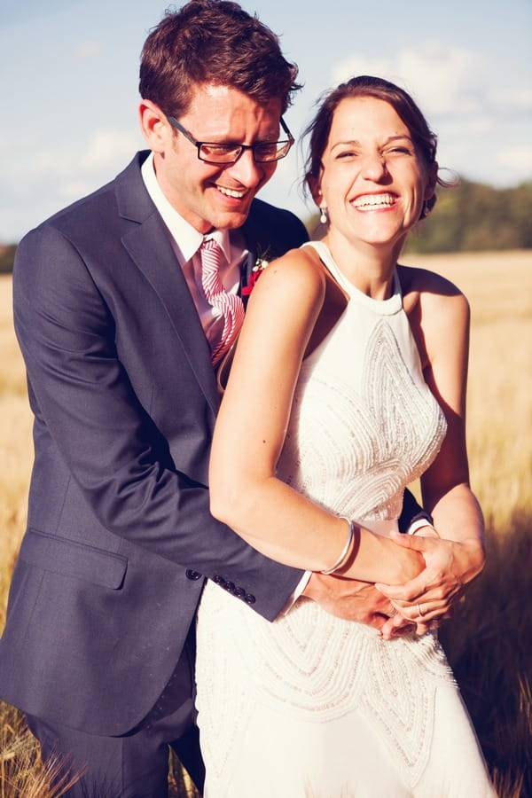 Bride and groom laughing together in field