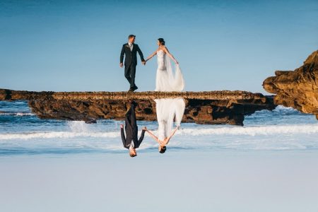 Reflection of bride and groom in sea - Picture by Estefania Romero Photography