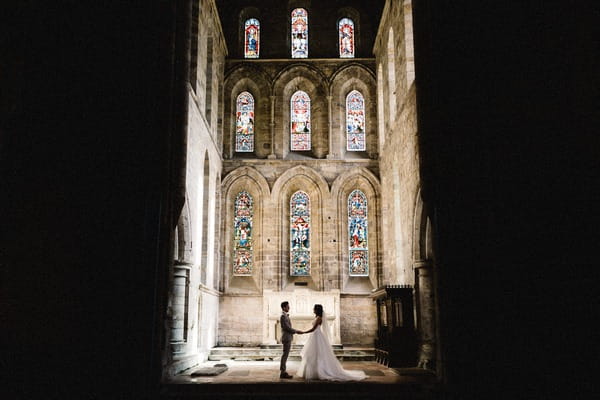 Bride and groom holding hands in church with light shining down on them - Picture by Andy Turner Photography