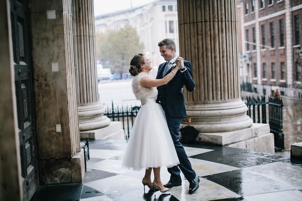 Bride and groom dancing in the rain at entrance to wedding venue - Picture by My Beautiful Bride