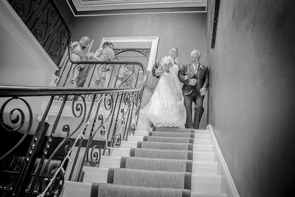 Father leading bride down the stairs