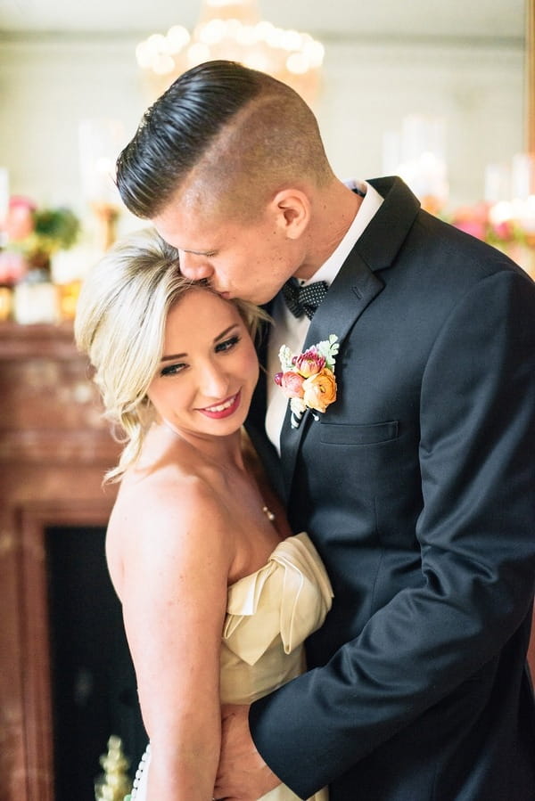 Groom kissing bride on head