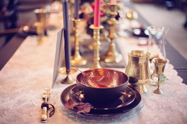 Wedding place setting with brass and dark crockery