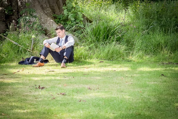 Best man sitting on grass practising speech