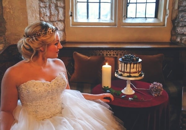 Bride sitting next to table with cake