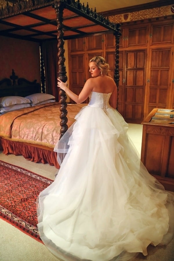 Bride holding onto post of bed