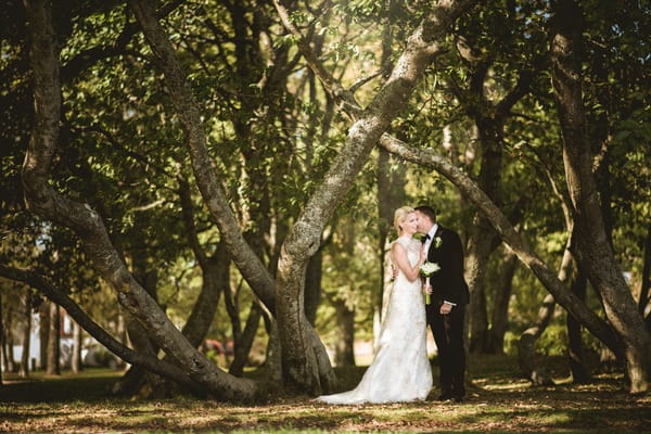 Bride and groom standing by trees - Picture by Natalie Johansson Fotograf