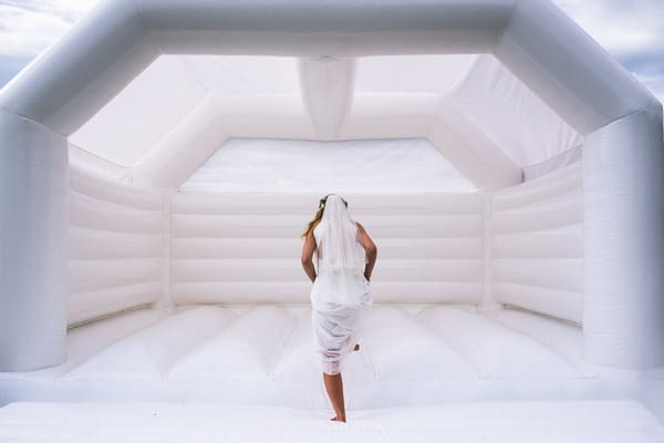 Bride getting on white bouncy castle - Picture by Kristian Leven Photography