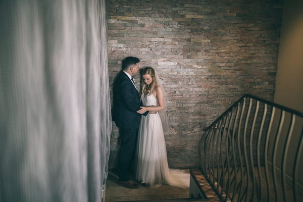 Bride and groom standing by wall at bottom of steps - Picture by Jess Yarwood Photography