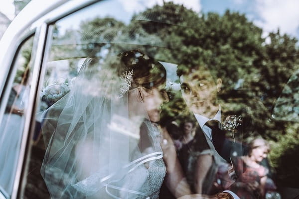 Bride and groom sitting in back of wedding car