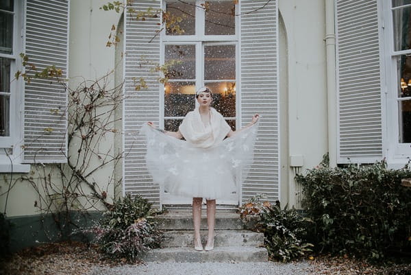 Bride holding out skirt of dress in snow