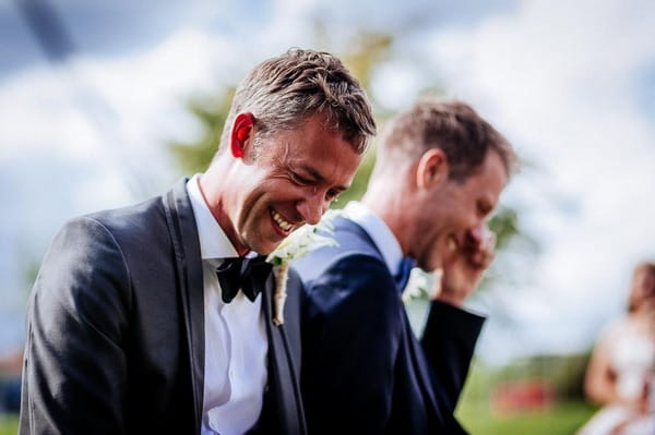 Grooms laughing and wiping away tears