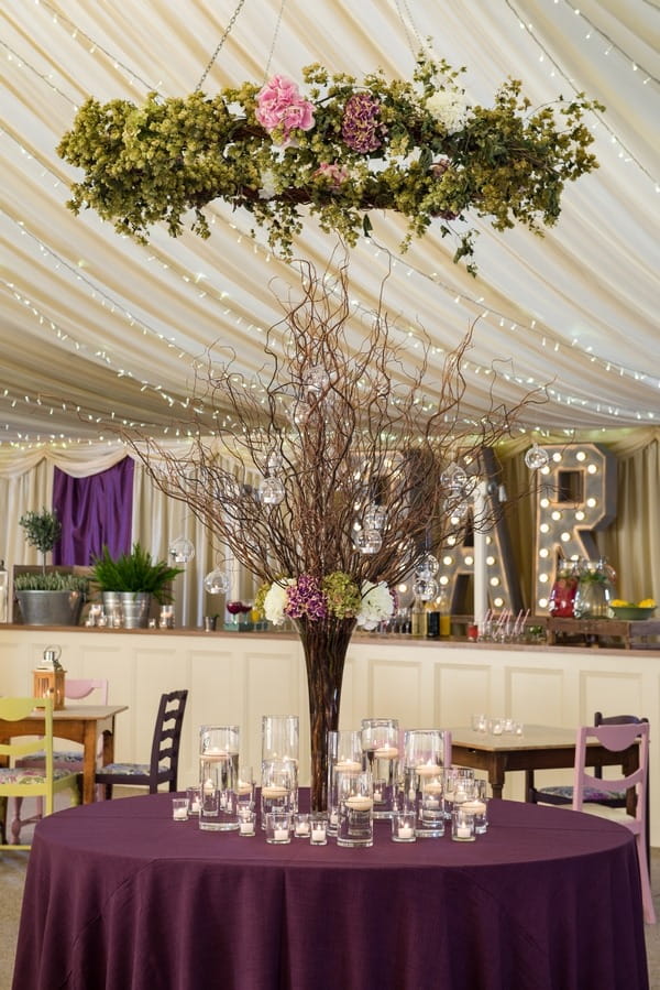 Tall wedding table centrepiece on purple tablecloth