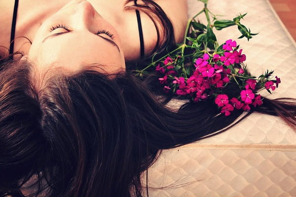 Teenager laying on bed next to flowers