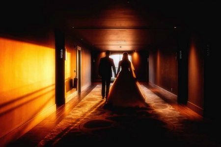 Bride and groom walking down sunlit corridor - Picture by David Walters Photography