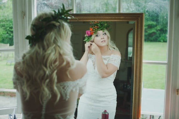 Reflection of bride in mirror putting on earrings