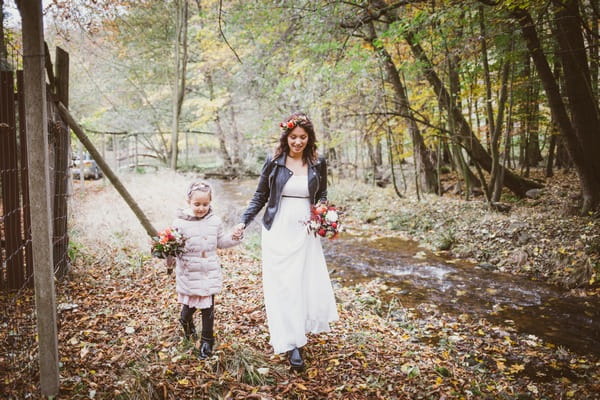 Bride walking through forest with flower girl