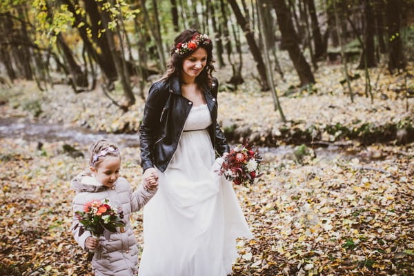 Bride and flower girl walking through forest