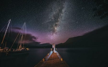 Bride and groom standing on jetty at night with incredible starry coloured sky - Picture by Richards and Co Photography