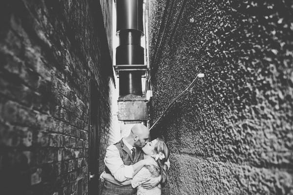 Bride and groom kissing down narrow alleyway - Picture by Helen Howard Photography