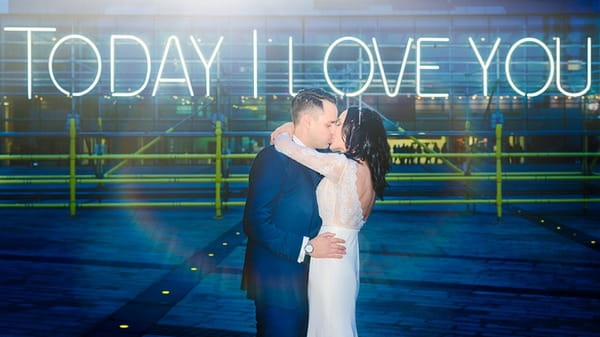 Bride and groom kissing in front of neon sign that says Today I Love You - Picture by Mick Cookson Photography