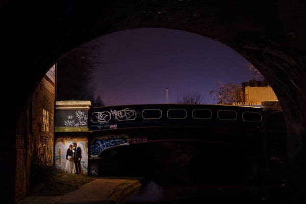 Bride and groom standing by bridge next to canal at night - Picture by Simon Dewey Photography