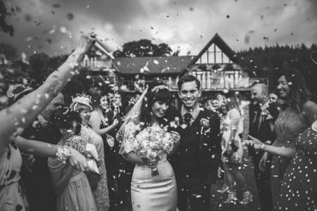 Bride and groom walking through shower of confetti - Picture by Lewis Fackrell Photography