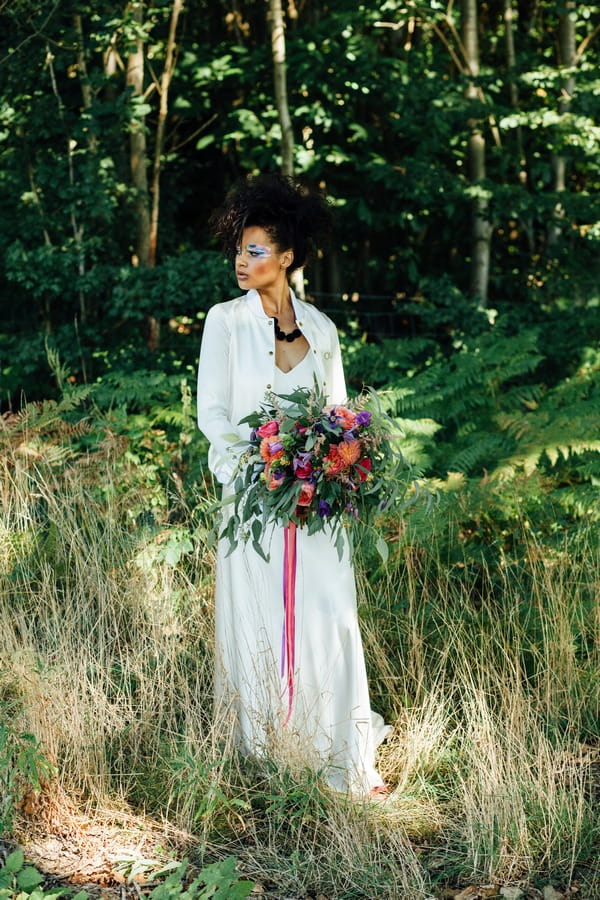 Bride standing in long grass holding bouquet