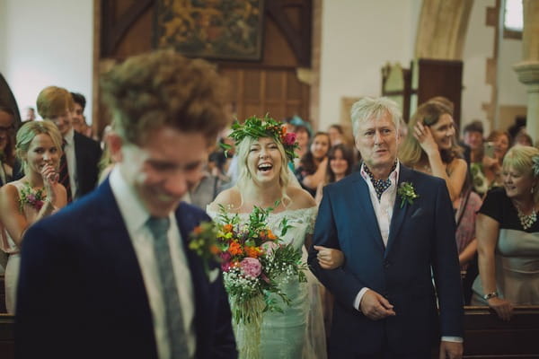 Bride laughing as she walks down the aisle