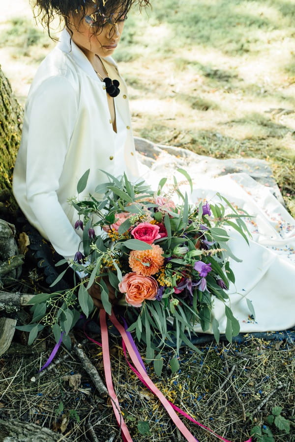 Bride sitting against tree