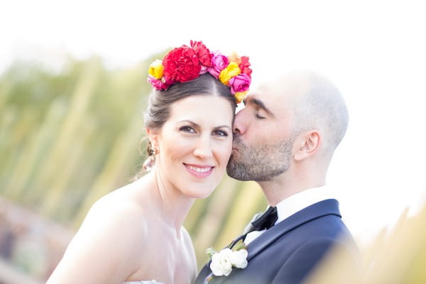Groom kissing bride with flower crown on cheek