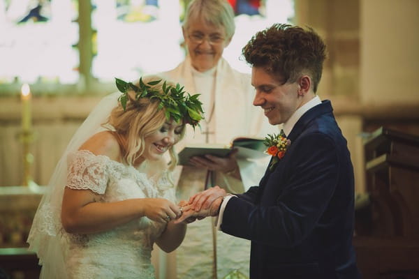 Bride putting ring on groom's finger