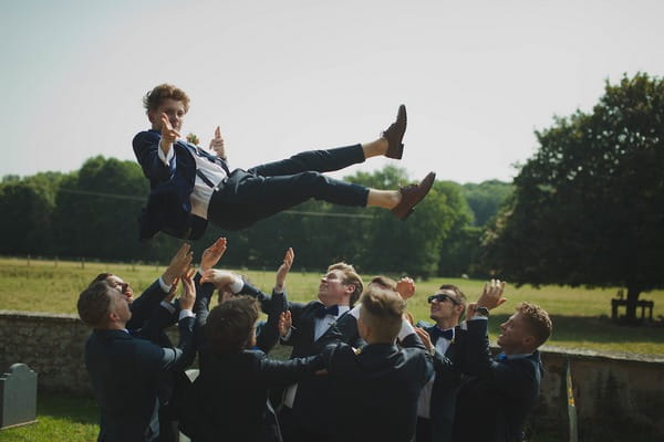 Groomsmen throwing groom in the air