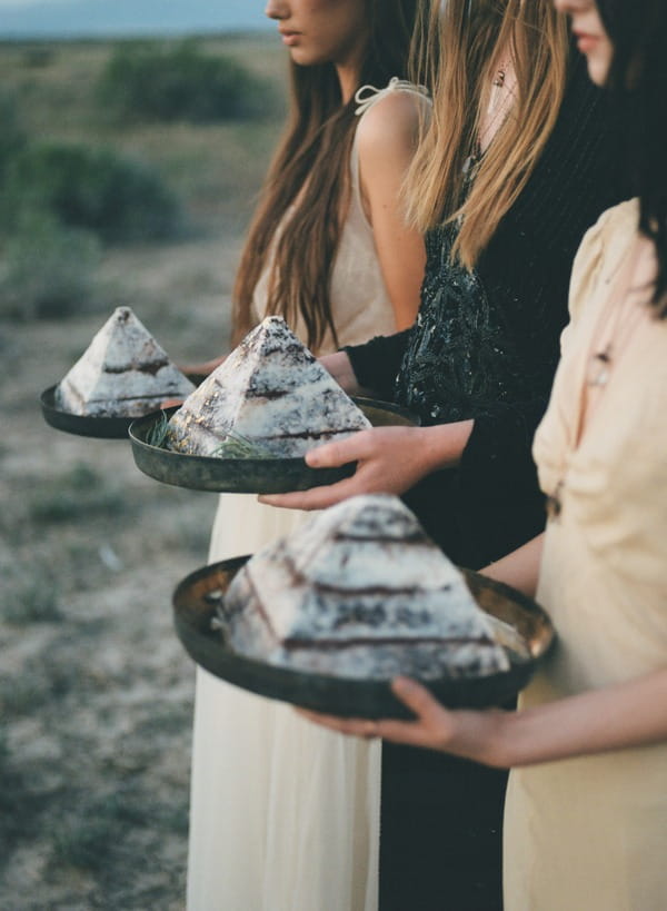 Three brides in row holding pyramid cakes