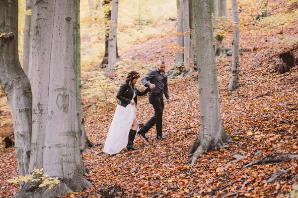 Bride and groom walking up slope in woods