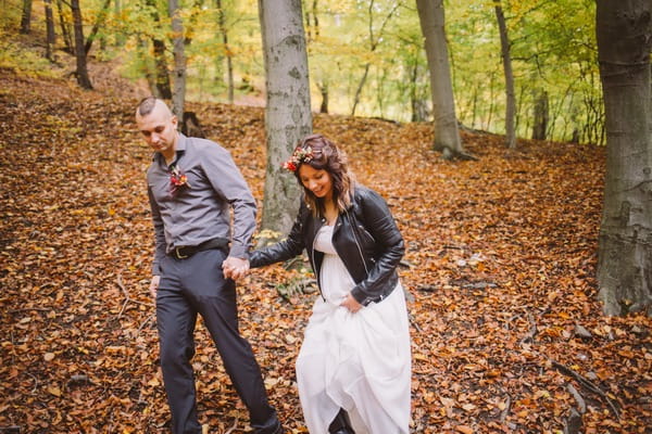 Bride and groom holding hands in forest