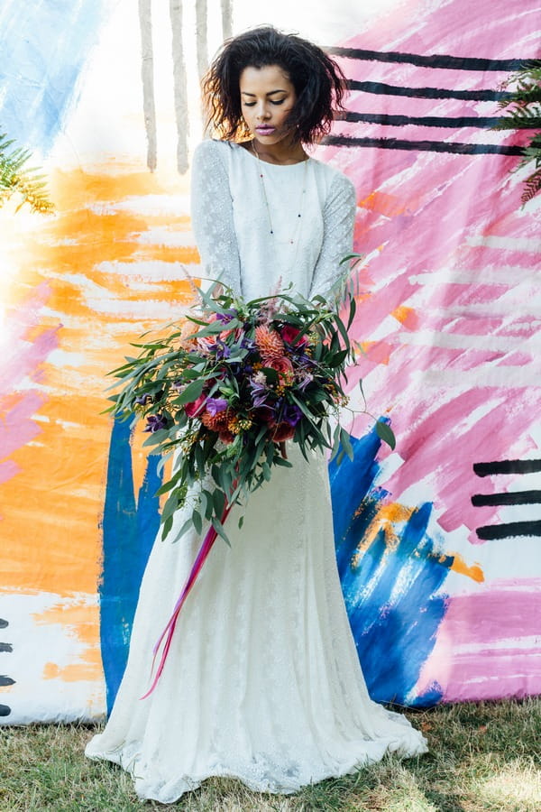 Bride holding bouquet against a colourful backdrop