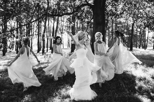 Bride and bridesmaids dancing under tree