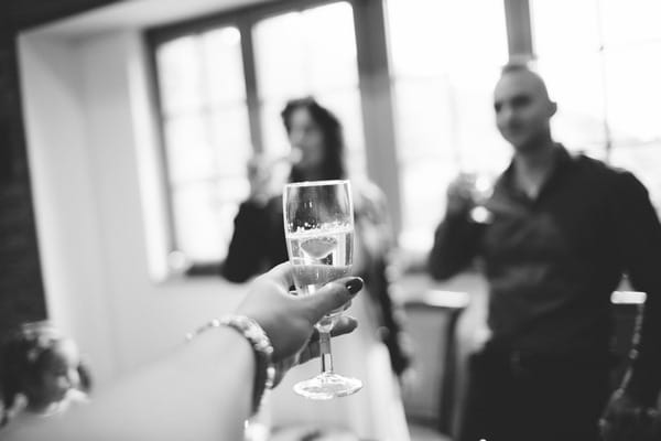 Arm holding out glass to toast bride and groom