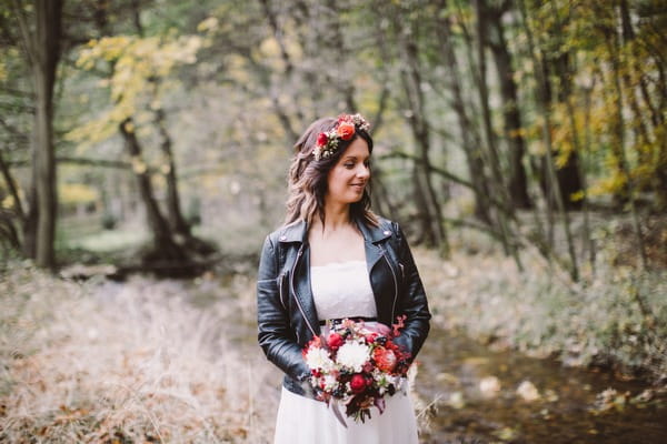 Bride standing by stream in forest