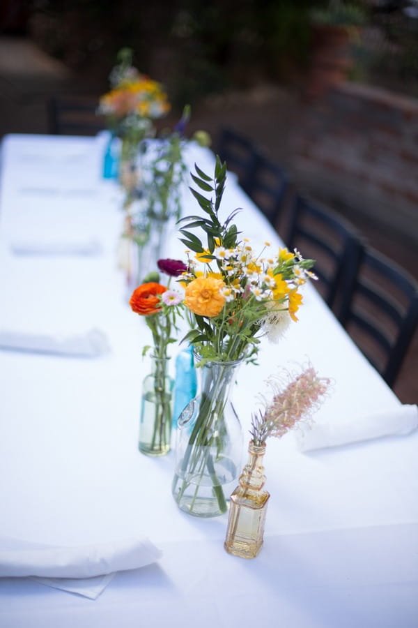 Vases of colourful flowers on wedding top table