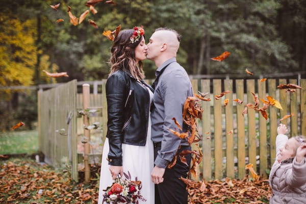 Bride and groom kissing whilst being showered with leaves