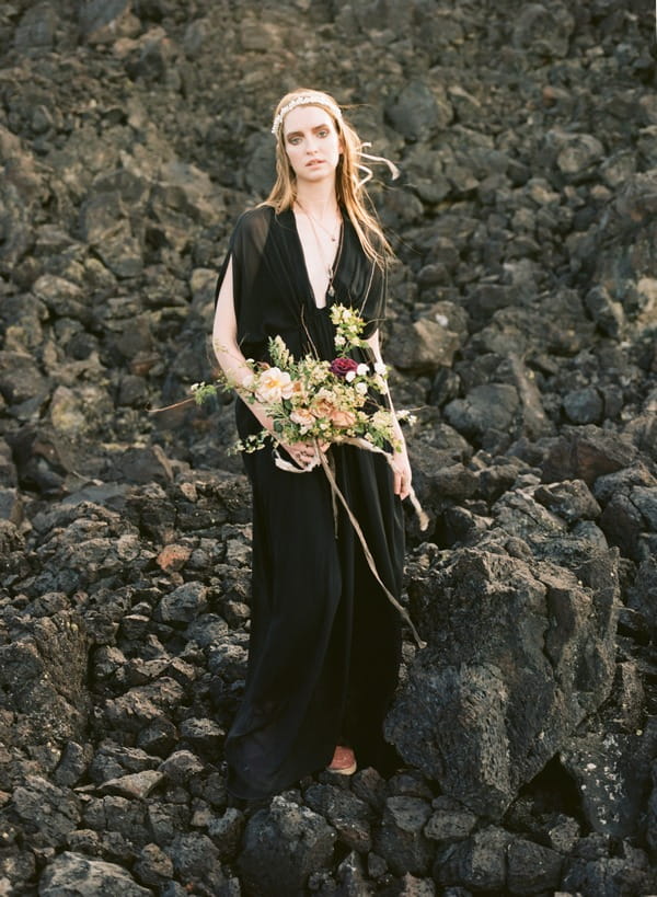 Bride in black dress standing on rocks