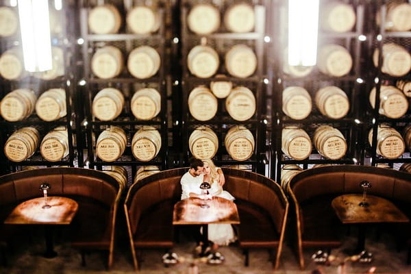 Bride and groom sitting in front of racks of barrels