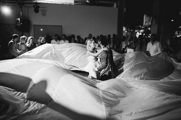 Bride and groom dancing in middle of parachute