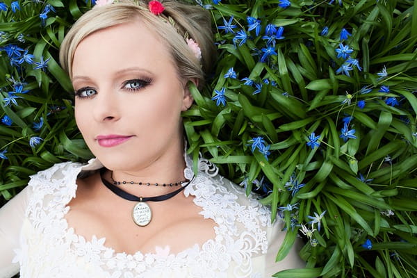 Bride wearing necklaces laying in long grass